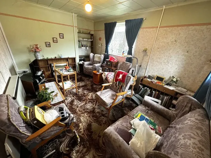 Before house clearance showing a cluttered lounge filled with furniture, belongings and unwanted items